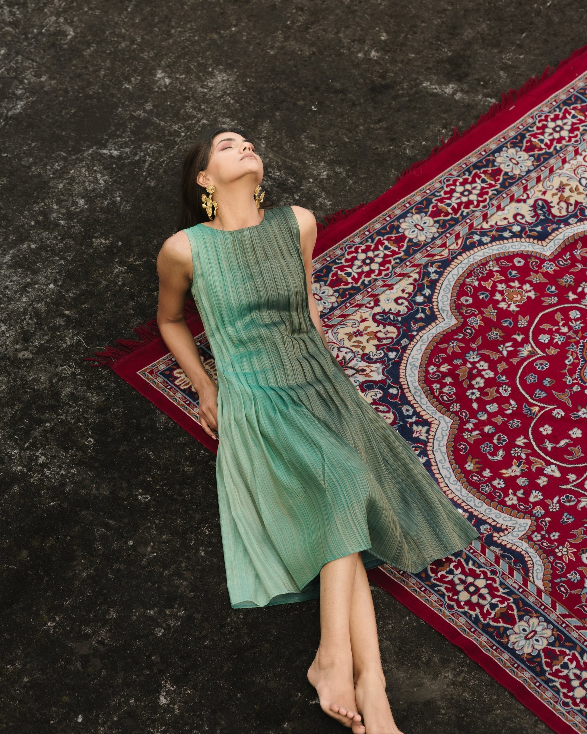 Model wearing teal pleated silk dress from Erised’s Gold Line Collection, featuring handwoven texture and sculptural pleats.