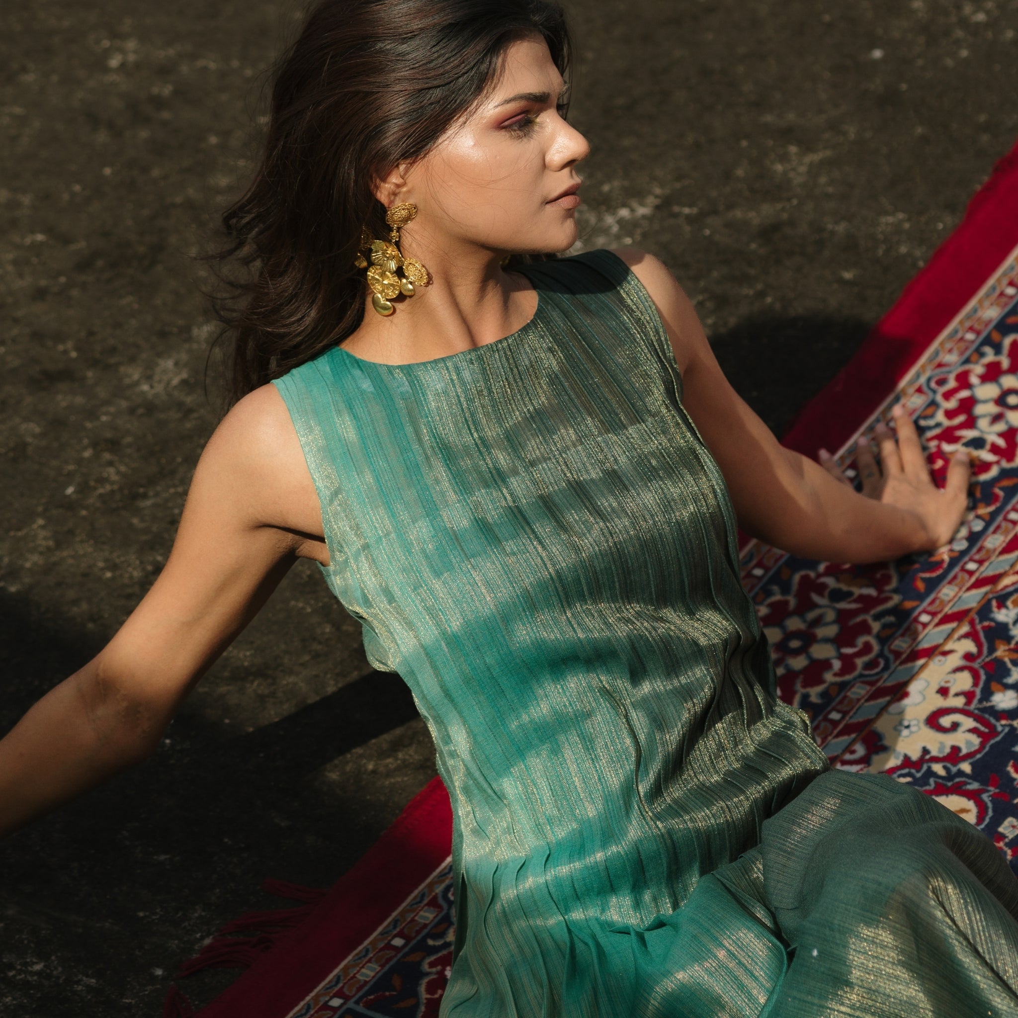 Model wearing teal pleated silk dress from Erised’s Gold Line Collection, featuring handwoven texture and sculptural pleats.