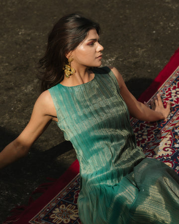 Model wearing teal pleated silk dress from Erised’s Gold Line Collection, featuring handwoven texture and sculptural pleats.