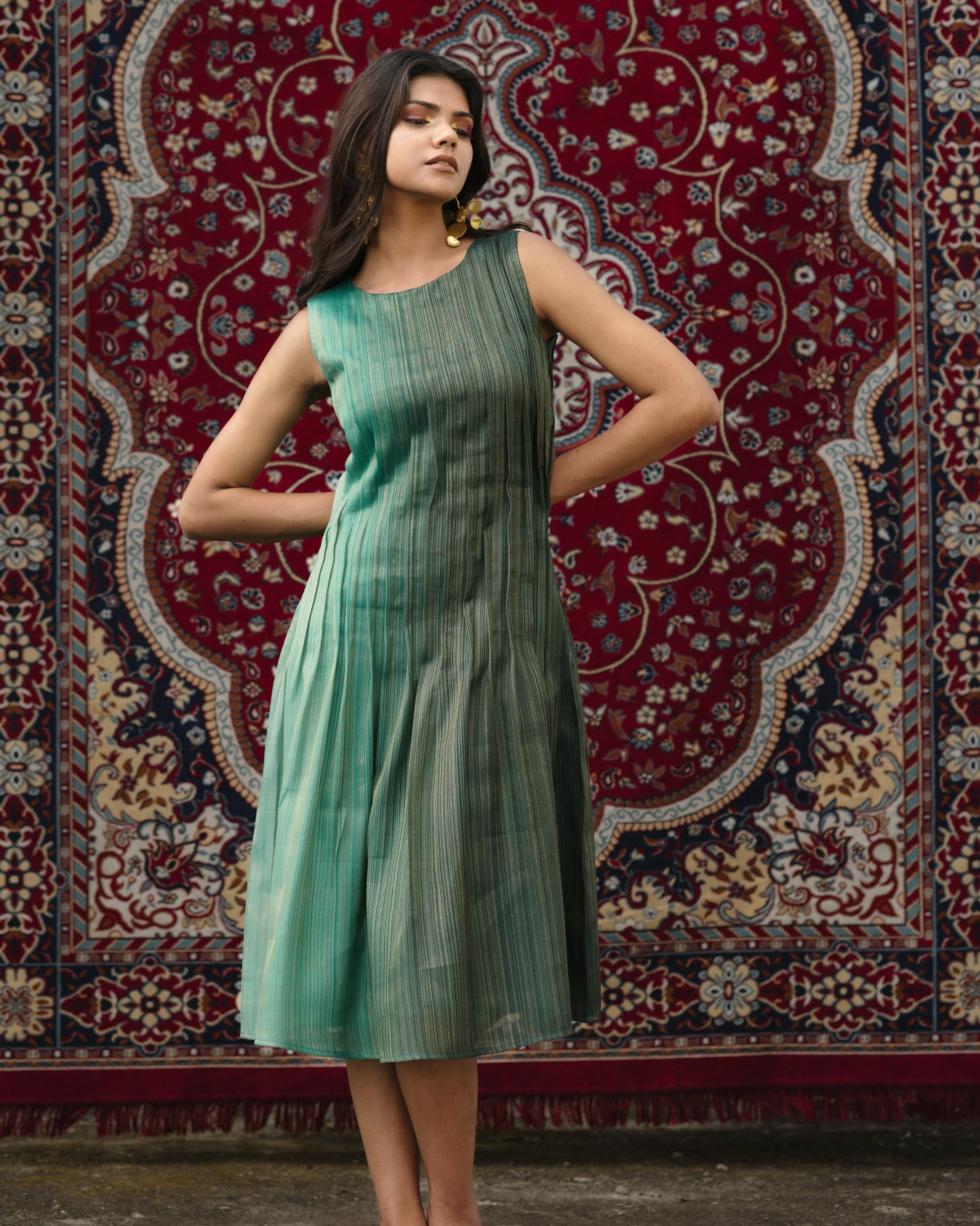 Model wearing teal pleated silk dress from Erised’s Gold Line Collection, featuring handwoven texture and sculptural pleats.