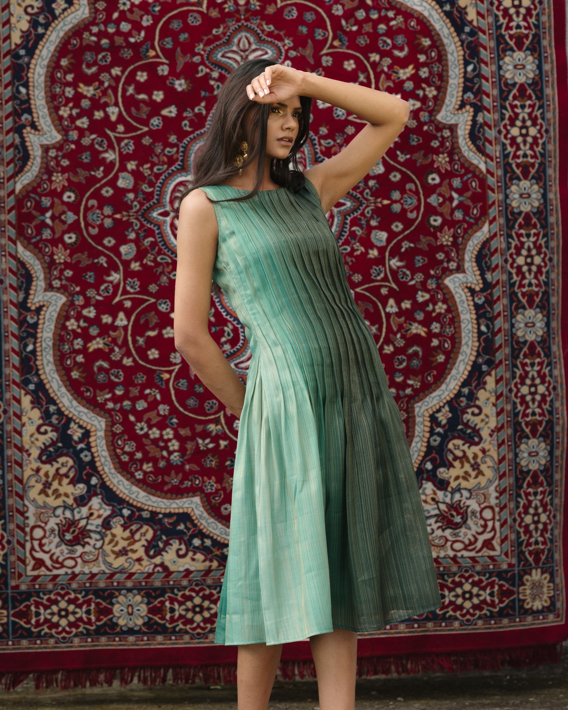 Model wearing teal pleated silk dress from Erised’s Gold Line Collection, featuring handwoven texture and sculptural pleats.