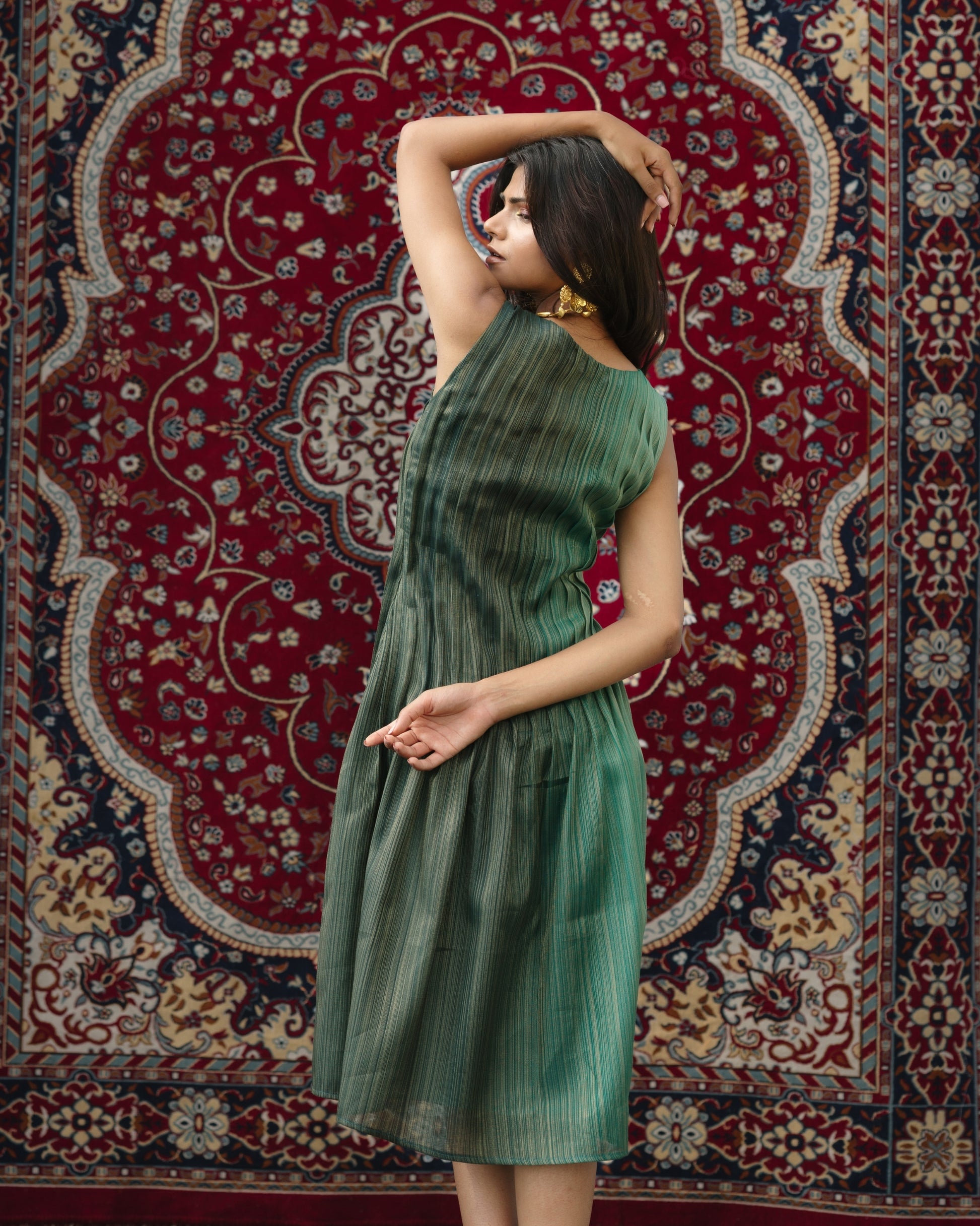 Model wearing teal pleated silk dress from Erised’s Gold Line Collection, featuring handwoven texture and sculptural pleats.