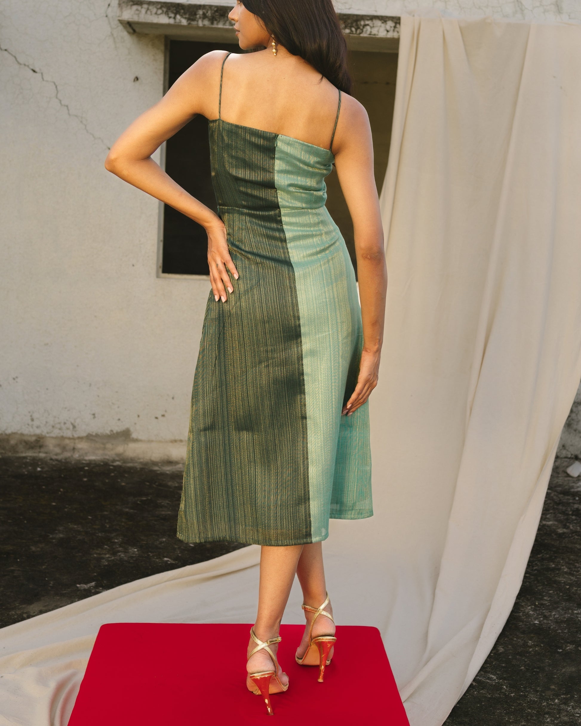 Model wearing teal handwoven bias-draped silk dress with spaghetti straps from Erised’s Gold Line Collection — modern festive luxury look.