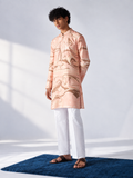 Model wearing a peach thigh-length kurta with all-over brown and ivory hand marbling, full sleeves and white trousers.