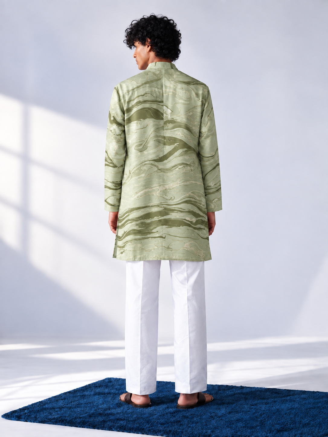 Model wearing a sage and olive hand-marbled thigh-length kurta with ivory accents, full sleeves and white trousers.