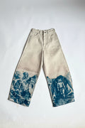 A pair of off-white barrel-leg jeans with blue vintage-style scenic prints on the lower legs, laid flat on a white background.