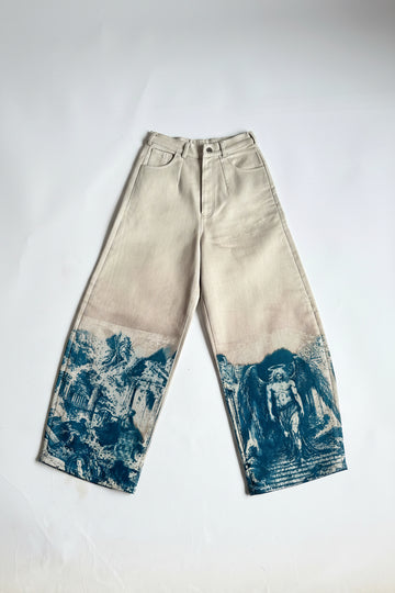 A pair of off-white barrel-leg jeans with blue vintage-style scenic prints on the lower legs, laid flat on a white background.